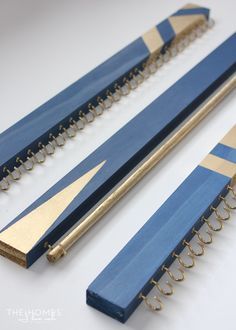 three pieces of blue and gold colored wood with holes in them on a white surface