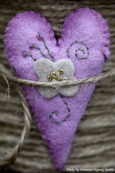 a purple heart with a bow on it hanging from a rope in front of a woven basket