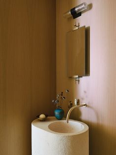 a bathroom sink sitting next to a mirror on a wall above it's faucet