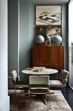 a dining room table with chairs and artwork on the wall above it, along with an area rug