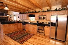 a kitchen with wood floors and stainless steel appliances in the center, along with an area rug on the floor