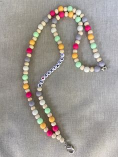 a multicolored beaded necklace with a name charm hanging from it's end