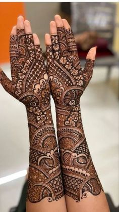 two hands with henna tattoos on them, one is showing off the intricate design