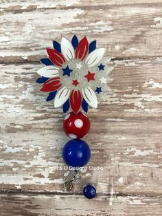 a red, white and blue beaded brooch on a wooden background with beads