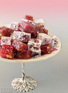 a white plate topped with red and yellow desserts on top of a cake stand