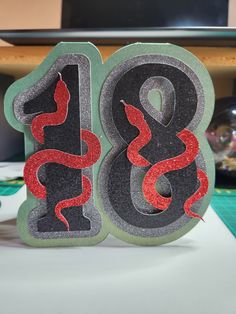 the number eight is decorated with red and black glitter