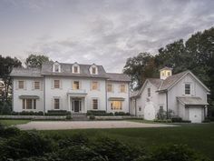 a large white house sitting in the middle of a lush green field