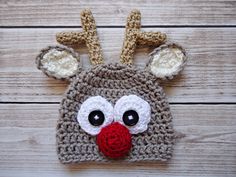 a crocheted reindeer hat with big eyes and nose is shown on a wooden surface