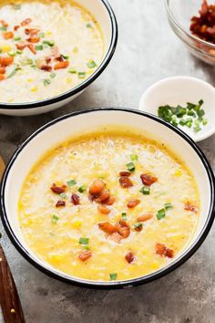 two bowls of soup with bacon, cheese and other toppings on the counter top