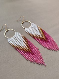 "Step into the realm of timeless elegance with our \"Aphrodite's Blush Fringe Earrings\". Handcrafted with love & precision, these earrings feature a palette of shimmering Miyuki beads in a harmonious blend of crystal white, sun-kissed gold & enchanting shades of pink. Their intricate brick stitch design, reminiscent of ancient Greek mosaics, adds a touch of elegance & sophistication. As these earrings dance gracefully with every movement, they radiate an aura of ethereal beauty that will captivate all eyes. Embrace your divine essence & let theses earrings be a whisper of beauty that echoes the allure & radiance of Aphrodite herself. *Miyuki Glass Beads *Stainless Steel Gold plated Earring hooks *Stainless Steel Gold plated Circle Link" White Beaded Earrings For Festivals, White Beaded Earrings For Festivals Gift, White Beaded Earrings For Festivals And Gifts, Traditional Pink Jewelry With Tiny Beads, Handmade White Chandelier Earrings For Festive Occasions, Handmade White Fusion Jewelry, Festive White Handmade Chandelier Earrings, Festive Handmade White Chandelier Earrings, White Dangling Beads Earrings For Festivals