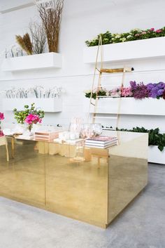 a gold table with flowers on it in a room filled with shelves and shelving