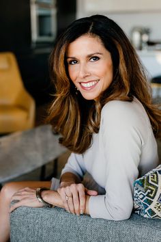 a woman sitting on a couch smiling at the camera