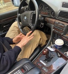 a man sitting in the driver's seat of a car holding his hand on the steering wheel