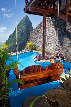 a wooden bench sitting in the middle of a swimming pool next to a mountain range