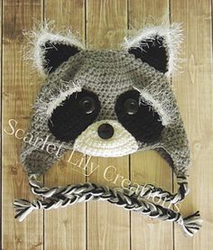 a crocheted raccoon hat on top of a wooden floor with a rope