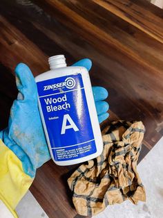 a bottle of wood bleach sitting on top of a wooden table next to a glove