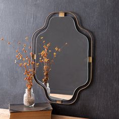 a mirror sitting on top of a table next to a vase with flowers in it