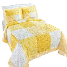 a yellow and white quilted bedspread with tassels