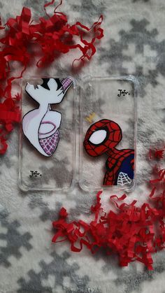 two cell phones with spiderman stickers on them next to red confetti