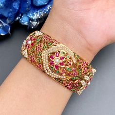 Featuring a broad gold plated silver jadau kada/bangle made on sterling silver with gold plating. It has been intricately studded with ruby like red stones, emerald like green stones and freshwater pearls. The bangle comes openable in size 2inch 5 anna and this design can be customized to your size. Ruby Jeweled Bangle For Wedding, Jadau Kangan, Ruby Bangle With Intricate Design For Gift, Intricate Design Ruby Bangle Jewelry, Kada For Women, Jadau Kada, 22k Gold Jewelry Necklaces, Like Green, Red Stones