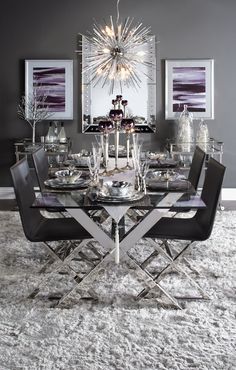 a dining room table is set with black chairs and silver plates on top of it