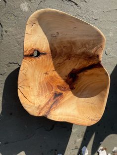 a wooden bowl sitting on top of a cement floor next to a wall with peeling paint