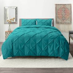 a bed with a turquoise comforter and pillows on top of it in a room