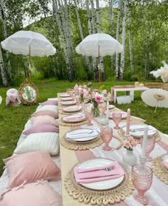 a table set up with pink and white plates, napkins and umbrellas