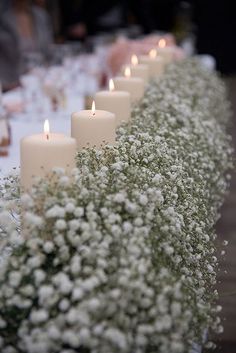 white flowers and candles are lined up on the table