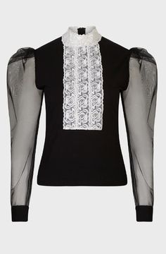 The EPOPEE is a black jersey pullover top with a center ribbon appliqué front made of a triple lace rose column that extends to create a mock neck. The pleated shoulders give way to a voluminous sheer sleeve that are finished with black jersey single French cuffs that allow for cufflinks. The EPOPEE features a hidden zipper at the back for closure. Luxury Black Top With Collared Neckline, Luxury Black Top With Lace Collar, Luxury Black Ruffled Blouse, Black Edwardian Blouse, Luxury Black Lace Sleeve Top, French Cuff, Sheer Sleeves, Mock Neck, Top Blouse