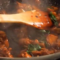 a wooden spoon stirring food in a pot