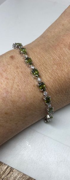 Vintage Peridot and Cubic Zirconia Rhodium Finished 925 Sterling Silver Tennis Bracelet The stones are deep colors and well matched.  The sterling silver is plated with rhodium to protect the bracelet from tarnish and give the appearance of white gold. 7.5 inches Our jeweler can shorten it for a $20 fee.  All jewelry is shipped free in the US in a nice gift box.   Check out our over a THOUSAND great reviews Engraving is $4 per letter and is not always perfect depending on the piece. It can take Green Sterling Silver Bracelets Fine Jewelry, Green Diamond Bracelet For Anniversary, Anniversary Green Sterling Silver Bracelets, Classic Green Stone Jewelry, Green Gemstone Diamond Bracelet, Certified Green Sterling Silver Bracelets, Green Oval Diamond Bracelet For Gift, Green Oval Diamond Bracelet Gift, Classic Green Sterling Silver Bracelets