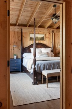 a large bed sitting inside of a bedroom on top of a wooden floor next to a white rug