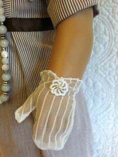 a close up of a person's hand wearing white gloves with pearls on it