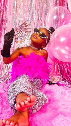 a woman in pink is laying on the floor with her feet up and some balloons behind her