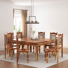 a wooden table and chairs in a room with hardwood floors, white walls and windows