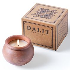 a candle that is next to a box on a white surface with the word dalit in it