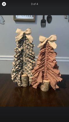 two small christmas trees sitting on top of a wooden table