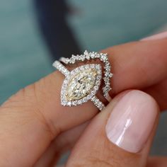 a woman's hand holding an engagement ring with a yellow diamond in the center