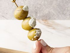 a hand holding an olive skewer with cheese on it