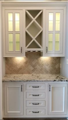 a kitchen with white cabinets and marble counter tops in the center is an open cabinet