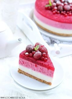 there is a piece of cheesecake with berries on top and another slice has raspberries