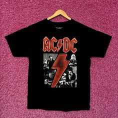 a black ac / dc t - shirt hanging on a pink wall