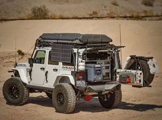 a white jeep parked in the desert with its roof open and it's lights on