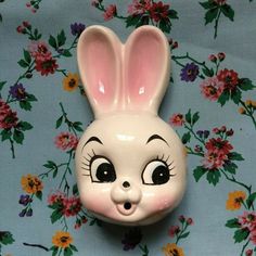 a ceramic rabbit head on top of a floral wallpaper