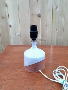 a bottle sitting on top of a wooden table next to a charger plugged in