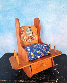 a wooden rocking chair with a cushion on it's seat and flowers painted on the back