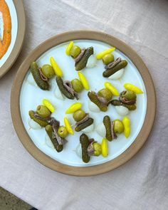 a plate with pickles and cheese on it next to a bowl of carrots