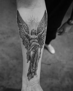 a black and white photo of an angel tattoo on the left arm, with wings spread out