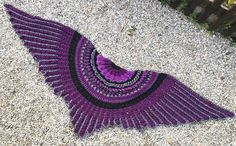 a purple and black knitted shawl laying on the ground